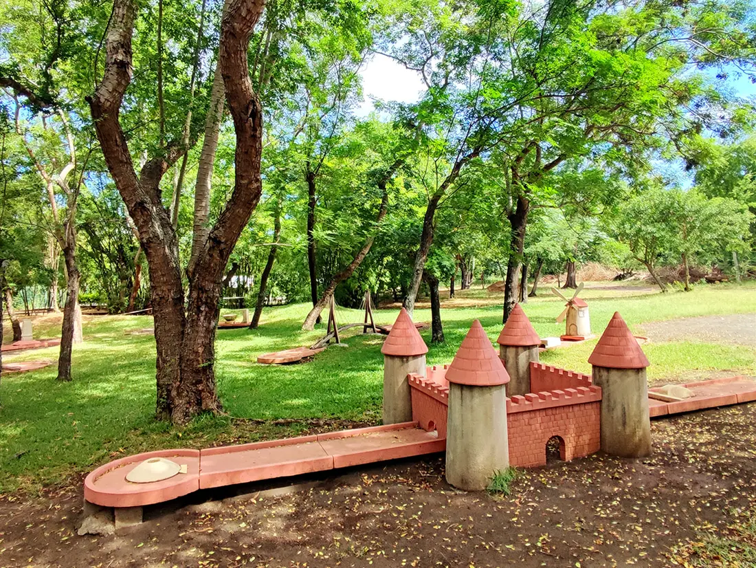 Le mini-golf de Croc Parc : obstacles en forme de châteaux aux toits rouges, sous les grands arbres de la forêt de L'Étang-Salé